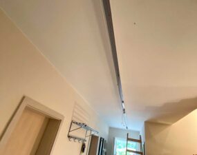 Eine Deckenschiene für Beleuchtung wird in einem Wohnraum montiert, eine Leiter steht bereit.