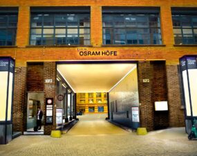 Von Lumeslicht beleuchteter Durchgang der ehemaligen Osram-Höfe in Berlin mit Sicht auf den Innenhof.