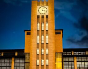 Von Lumeslicht beleuchteter Uhrturm der Osram-Höfe in Berlin bei Nacht.