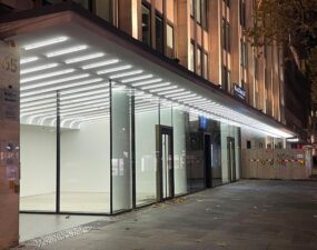Von Lumeslicht beleuchtete Glasfassade mit linearem LED-Deckenraster an einem Gebäude am Kurfürstendamm in Berlin.